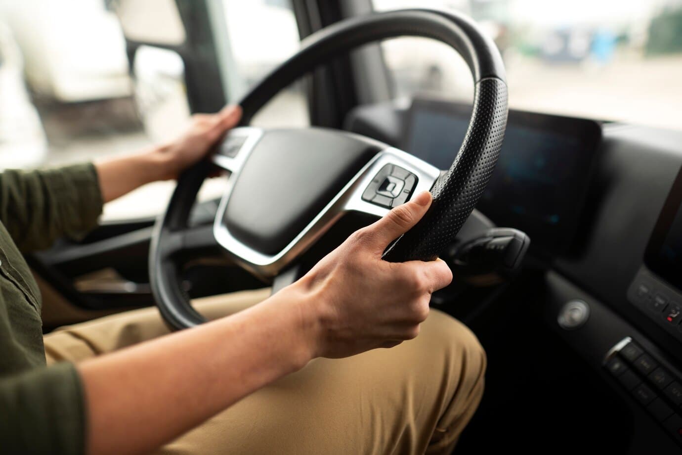 Hænder på et rat i et køretøj, der repræsenterer tidsregistrering for chauffører.