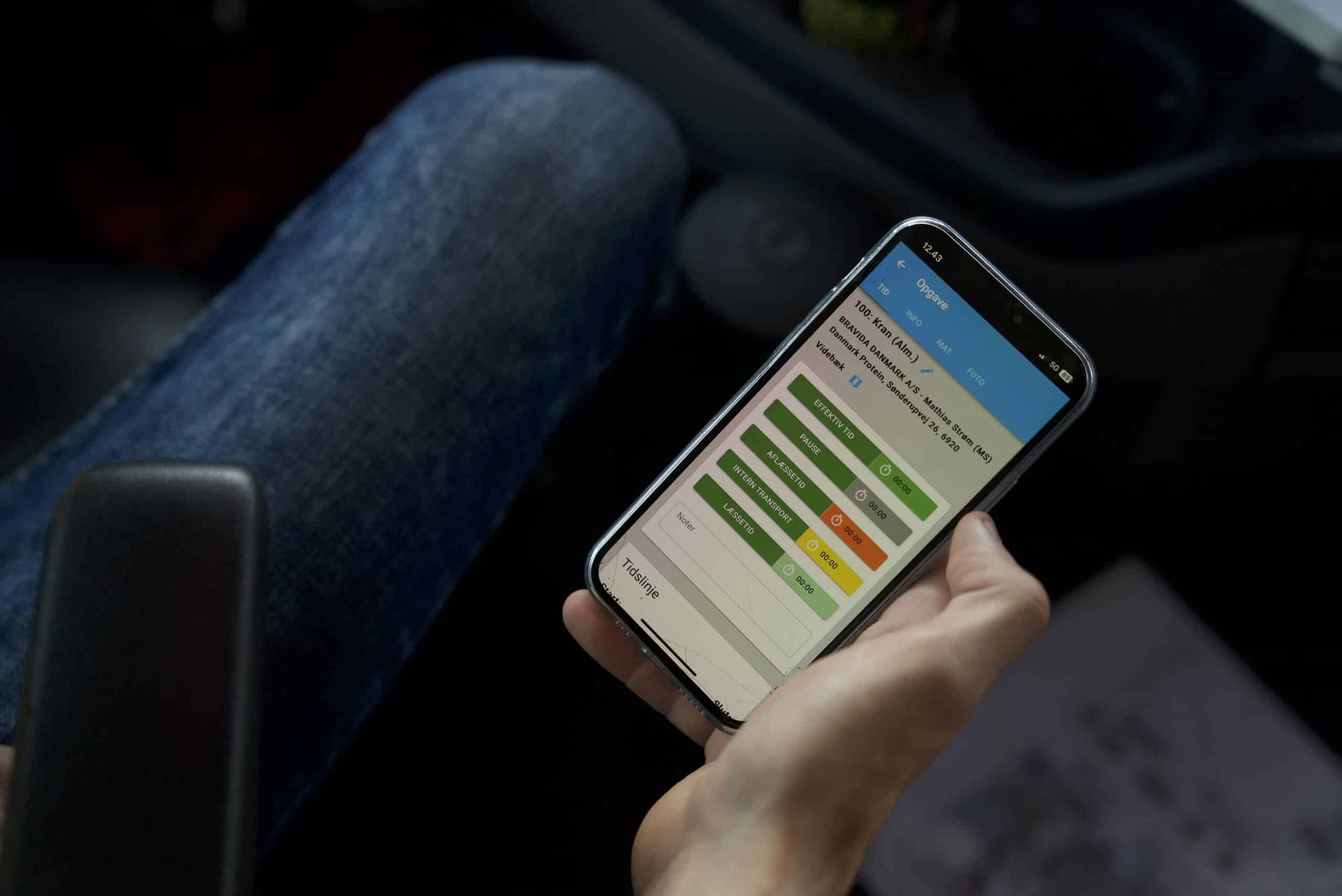 En chauffør holder CustomOffice app'en til tidsregistrering