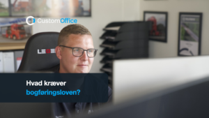 Ejer ved skærmen på kontoret med dokumentbakker og ringbind bagved. Tekst: Hvad kræver bogføringsloven?